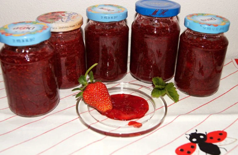 Domácí jahodová marmeláda v sáčcích na bílém ubrusu.