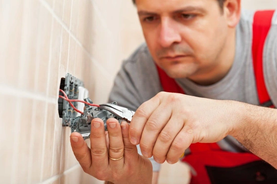 Elektrikář zapojuje zásuvku na dlažděnou stěnu