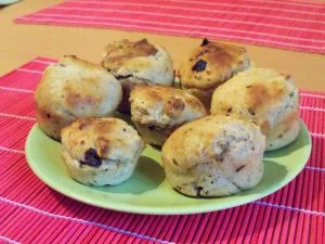 Zelený talíř s pečenými tvarohovými muffiny na růžovém podkladu.
