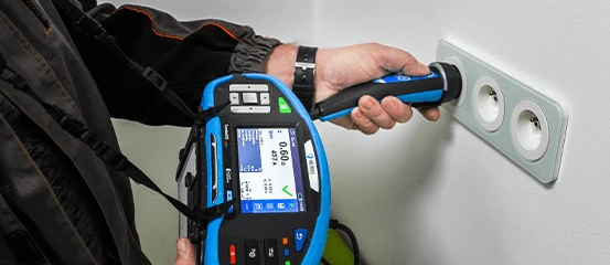 Elektrikář kontroluje zásuvku při revizi elektroinstalace