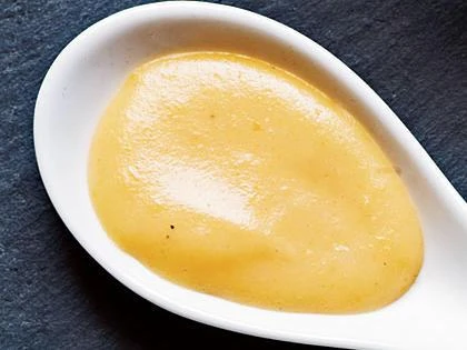 Hot cheddar omáčka v bílé misce na tmavém podkladu.