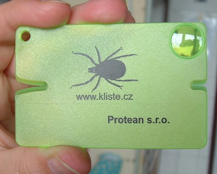 Zelený nástroj na vyjmutí klíště s logem a webovou adresou