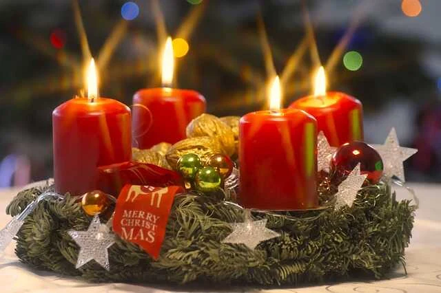 Adventní věnec s čtyřmi zapálenými svíčkami a vánočním zdobením