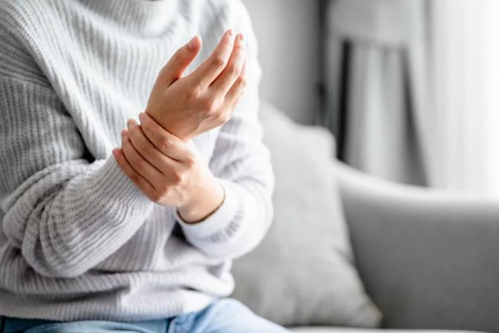 Osoba drží zápěstí, jako by měla bolest nebo příznaky neuropatie