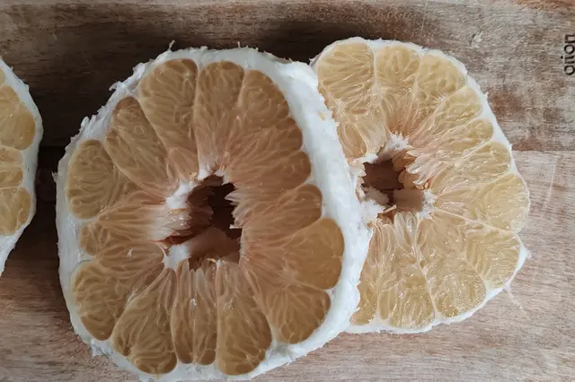 Pomelo nakrájený na polovinu, viditelné segmenty a bílá dužnina