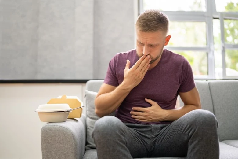 Muž trpící na stresový reflux po jídle z rychlého občerstvení
