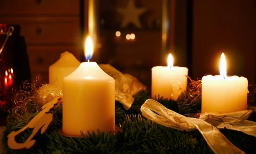 Zapálené svíčky na adventním věnci s vánočními ozdobami