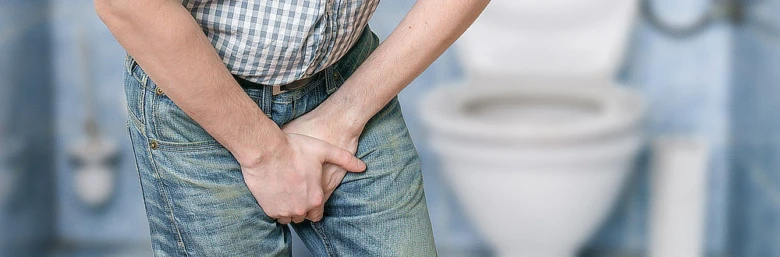 Muž drží břicho a pohlavní orgány, bolest při močení