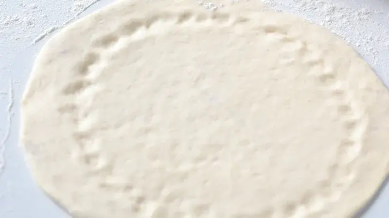 Kynuté těsto na pizzu roztažené na prášku
