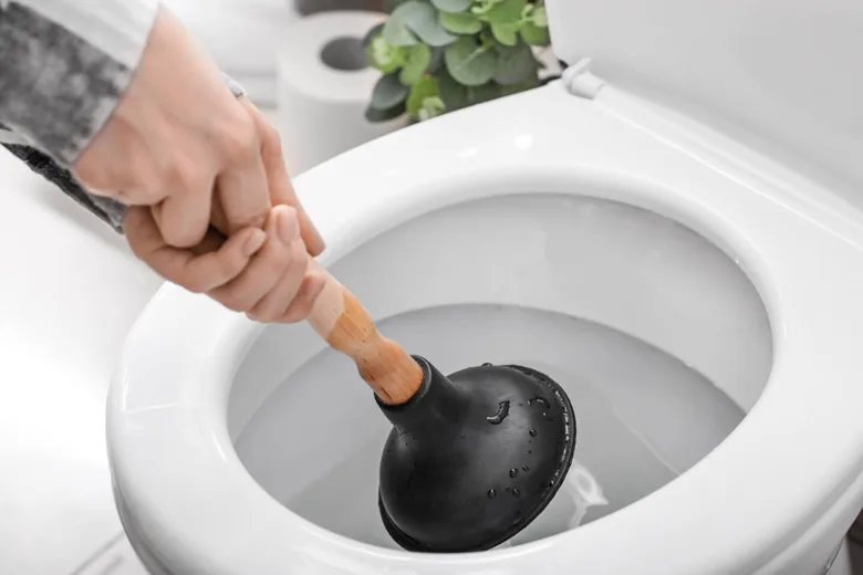 Člověk používá hadicový válec na záchod.