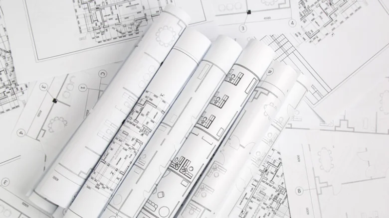 Rozložené a svázané stavební plány s architektonickými nákresy