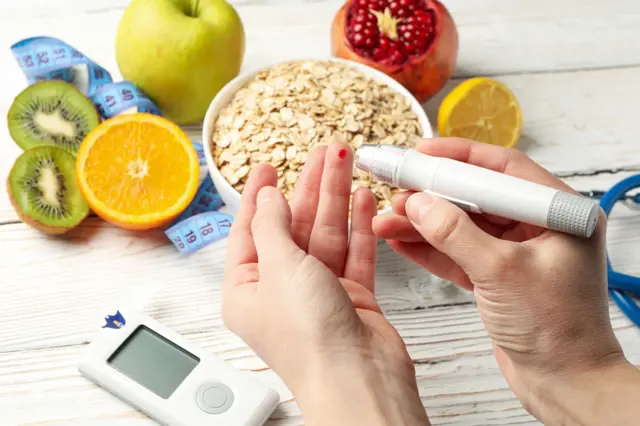 Ruce měří krevní cukr s ovocem pro diabetiky