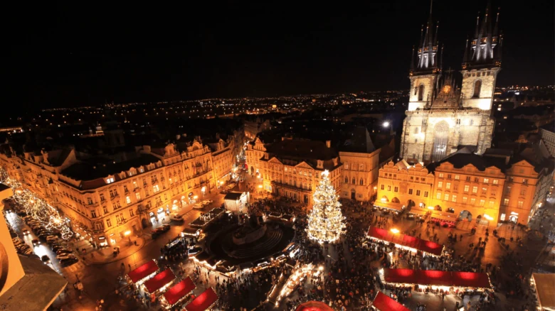 Vánoční trhy na Staroměstském náměstí v Praze s osvětlenou vánoční stromem a kostelem Panny Marie před Týnem