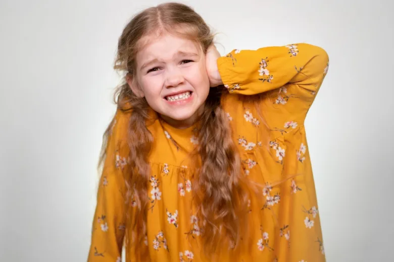 Dívka s bolestí ucha drží ruku u ucha