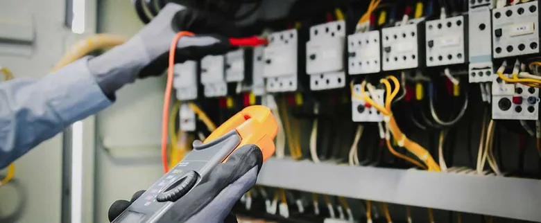Elektrikář měří napětí v rozvaděči při revizi elektroinstalace.