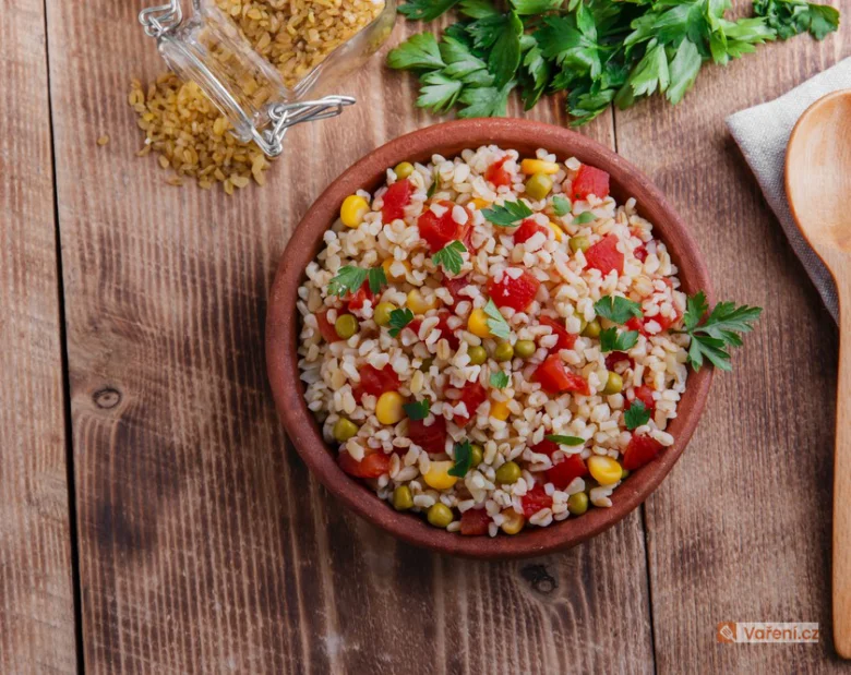 Bulgur se zeleninou v keramické mísce na dřevěném stole