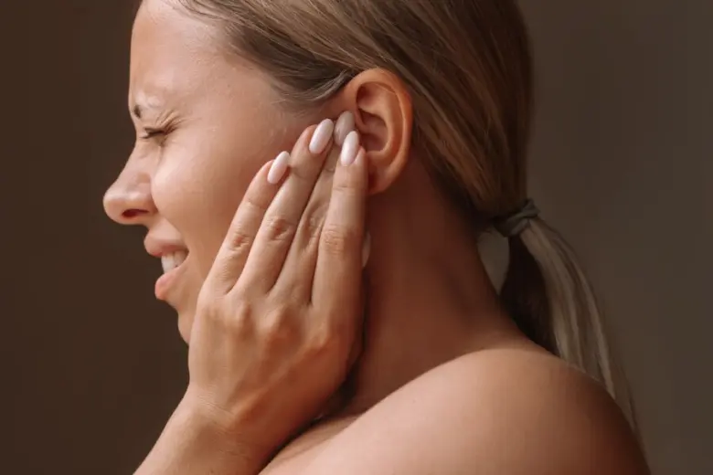 Žena s bolestí ucha drží ruku u ucha