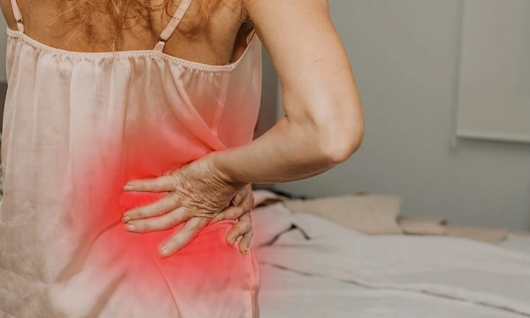 Žena s bolestí v dolním zádech, při které se drží boku