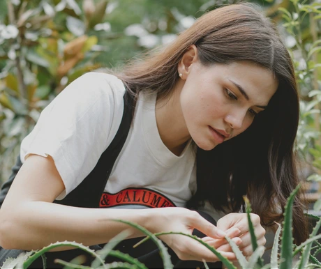 Žena si prohlíží listy rostliny aloe vera v zahradě