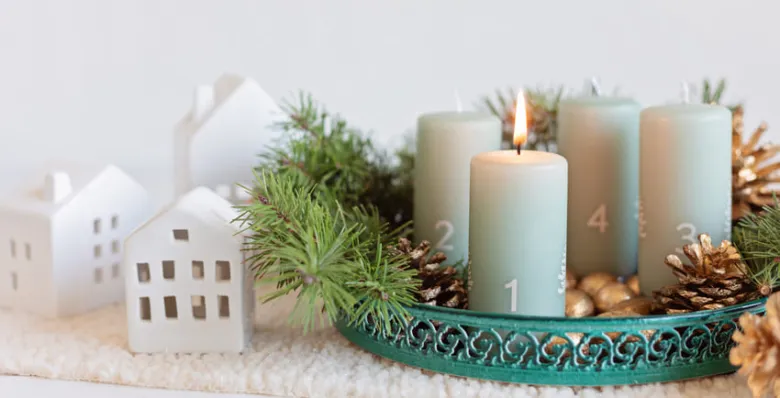Adventní věnec s zapálenou první svíčkou a vánoční dekorací