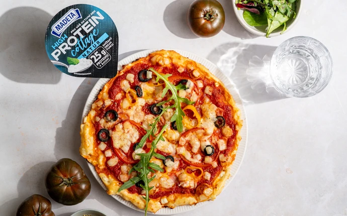 Pizzová půlka s tvarohem, olivami a rukolou na talíři