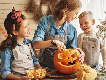 Rodina vyřezává dýni na Halloween v kuchyni.