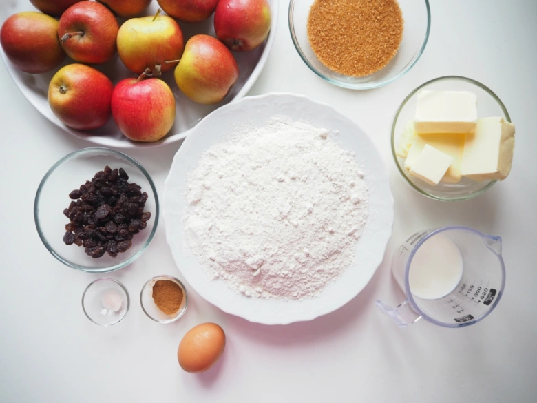 Ingredience na jablečný koláč: jablka, mouka, máslo, cukr, vajíčko, mléko, ořechy a koření
