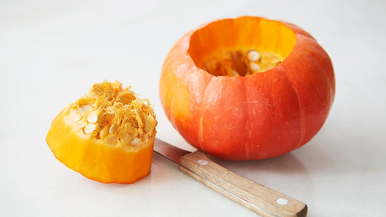 Pumpkin carving preparation showing hollowed-out gourd and tools.