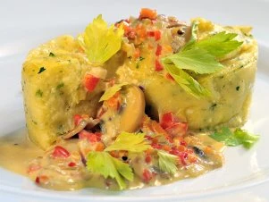 Hotová polenta s houbami a bylinkami na talíři.