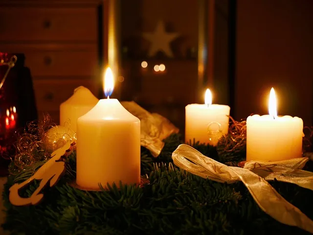 Zapálené svíčky na adventním věnci s jehličím a stuhami