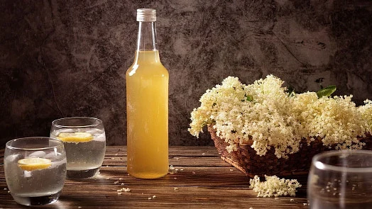 Sirup z černého bezu v lahvi s květy a připravenými nápoji