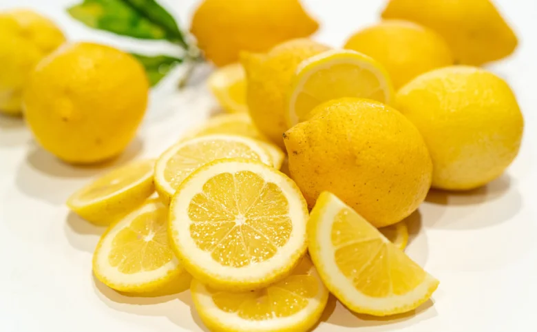 Žluté citrony celé a nakrájené na bílém pozadí