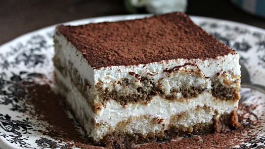 Kousek tiramisu s kakaovým práškem na talíři