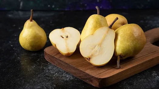 Zralé hrušky na dřevěné desce, některé nakrájené