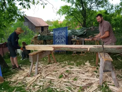 Dva lidé píli dřevo venku na zahradě.