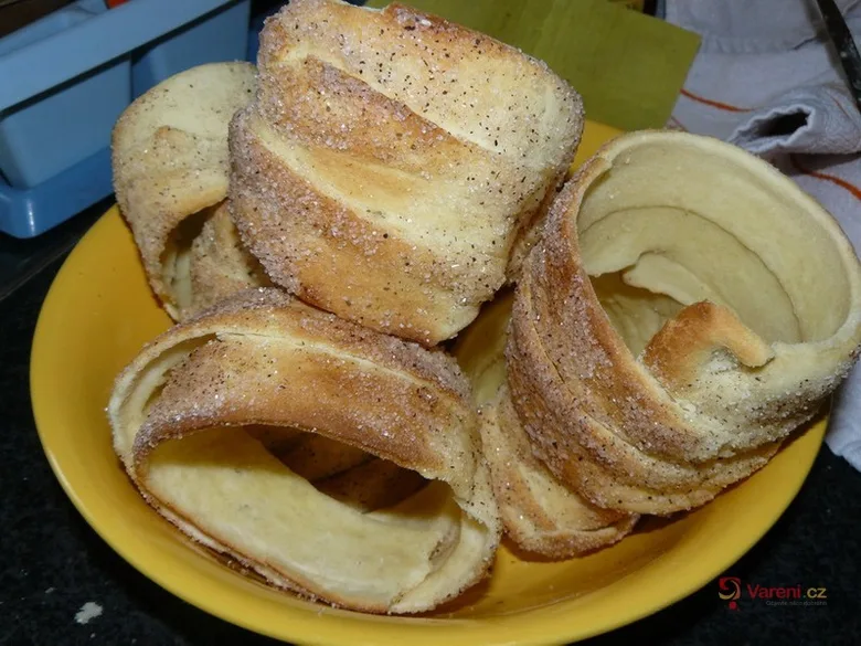 Zlatohnědé svitky s cukrem a pepřem na žlutém talíři.