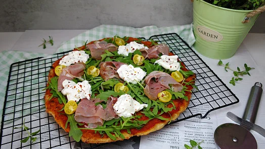 Pizza s tvarohem, šunkou a rukolou na chladícím mřížku