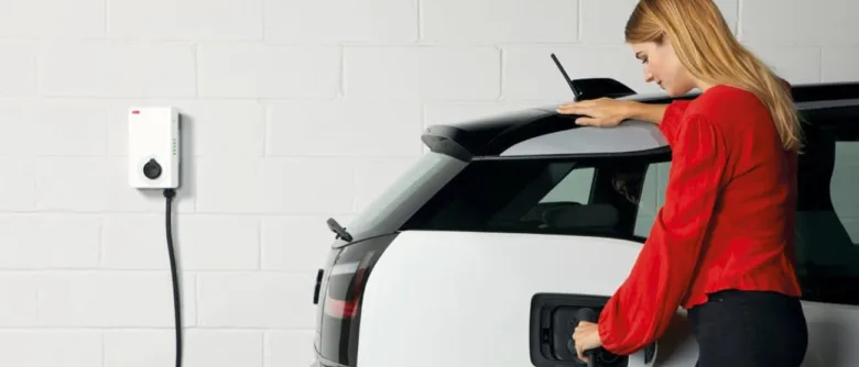 Žena nabíjí elektromobil doma pomocí stěnového nabíječky