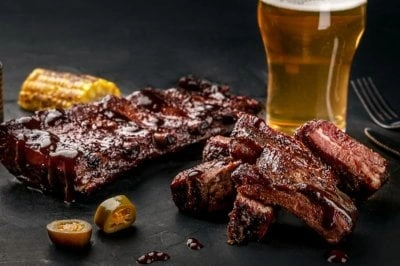 Pečená žebra s omáčkou, kukuřicí a pivem na talíři.